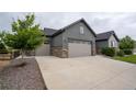 Three-car garage with stone accents, with a large driveway and landscaping at 11259 Kalispell St, Commerce City, CO 80022