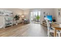 Living room with wood-like floors, balcony access, and a wall-mounted television at 13606 E Bates Ave # 208, Aurora, CO 80014