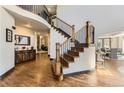 Grand foyer with curved staircase, hardwood floors, and views into the living and dining areas at 5352 Pinyon Jay Rd, Parker, CO 80134