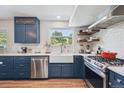 Stylish kitchen featuring blue cabinetry, stainless steel appliances, floating shelves, and a farmhouse sink at 8445 Lamar Dr, Arvada, CO 80003