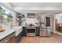 Modern kitchen with stainless steel appliances, white countertops, tile backsplash, and wood-look flooring at 8445 Lamar Dr, Arvada, CO 80003
