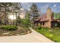 Inviting home with a stone chimney, copper roof, and a welcoming walkway amidst lush greenery and sunlit trees at 116 Ramona Rd, Golden, CO 80403
