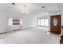 Bright living room featuring white carpet, chandelier, and large windows at 11686 W 74Th Way, Arvada, CO 80005