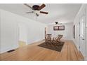 Bright living room featuring hardwood floors, ceiling fans, white walls, and charming vintage furnishings at 3225 S Sherman St, Englewood, CO 80113