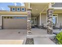Inviting covered front porch with stone pillar accents and seating area at 5495 Espana Ct, Denver, CO 80249