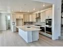 Bright kitchen with stainless steel appliances, a large island with a sink, and light hardwood flooring at 9382 Quaker St, Arvada, CO 80007