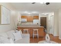An open kitchen featuring a breakfast bar, hardwood floors, and modern decor with easy access to the living room at 9650 Huron St # 12, Thornton, CO 80260