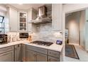 Modern kitchen with a gas cooktop, stainless steel range hood, and gray backsplash at 10291 E Powers Ave, Greenwood Village, CO 80111