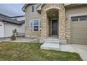 Inviting front porch with stone pillars and a modern light fixture. Well-maintained lawn at 3140 Newfound Lake Rd, Berthoud, CO 80513