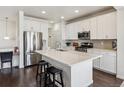 Bright kitchen features white cabinets, stainless steel appliances, and a large center island with bar seating at 12597 W Big Horn Cir, Broomfield, CO 80021