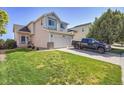 Charming two-story home with a well-maintained lawn and a long driveway with a truck parked on it at 10521 Taylor Ave, Firestone, CO 80504