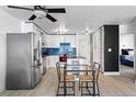 Open kitchen area with stainless steel appliances, white cabinets, and a dining table set for two at 1121 Albion St # 210, Denver, CO 80220
