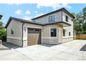 Attached garage featuring a wide driveway and modern exterior lighting at 3226 W Dakota Ave, Denver, CO 80219