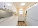 Cozy kitchen featuring a breakfast bar, a window overlooking the front yard, white appliances, and wood-look vinyl floors at 9005 E Lehigh Ave # 16, Denver, CO 80237