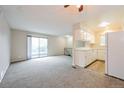 Bright living room with fresh carpeting, a sliding glass door to the balcony, and an open layout with views into the kitchen at 9005 E Lehigh Ave # 16, Denver, CO 80237