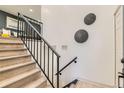 Elegant staircase features wooden steps, a sleek black railing, and decorative wall art at 5721 W 92Nd Ave # 96, Westminster, CO 80031