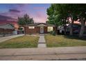 Charming brick home with a well-manicured lawn, mature trees, and a walkway leading to the front door at 7691 Osage St, Denver, CO 80221