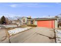 House exterior showcasing a green color scheme, orange garage door, and snowy yard at 4658 S Alkire St, Morrison, CO 80465