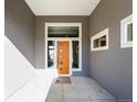 Modern entryway with vibrant orange door, transom window, and neutral wall color at 4585 Mesa Top Dr, Monument, CO 80132