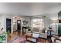 Bright living room featuring hardwood floors, large window, and cozy seating area at 6111 W Maplewood Pl, Littleton, CO 80123