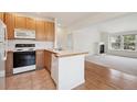 Bright kitchen with wood cabinets, a center island, and modern appliances at 6803 W Yale Ave, Lakewood, CO 80227