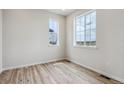 Bright bedroom featuring two windows and elegant wood-look flooring at 14400 Heritage Dr, Mead, CO 80504