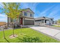 Two-story house with gray siding, red front door, and landscaping at 13567 Valentia St, Thornton, CO 80602