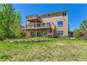 A spacious backyard features a multi-level deck, green grass, and a charming rock retaining wall, perfect for outdoor living at 1905 Graphite Ct, Castle Rock, CO 80108