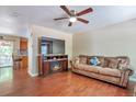 Comfortable living room featuring a cozy fireplace, hardwood floors, and a ceiling fan for added comfort at 12333 Newport Ct, Brighton, CO 80602
