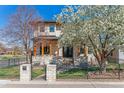 Beautiful two-story home with a well-manicured lawn and a charming stone facade and flowering tree at 2600 S Adams St, Denver, CO 80210