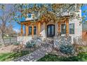 Inviting two-story home featuring stone accents, a covered porch, and landscaped front yard with mature trees at 2600 S Adams St, Denver, CO 80210