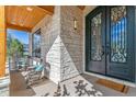 Charming front porch with stone columns, wood ceiling, rocking chairs, and an ornate front door at 2600 S Adams St, Denver, CO 80210
