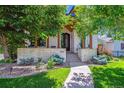 Charming two-story home with stone accents, mature trees, landscaped yard, and walkway at 2600 S Adams St, Denver, CO 80210