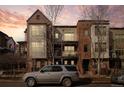 Multi-story townhome with brick and siding, a small balcony, against a dramatic evening sky at 437 S Reed Ct, Lakewood, CO 80226