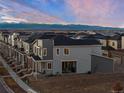 Back exterior view of a modern home showing the patio area, windows, and a glimpse of the mountain landscape at 5351 Warrior St, Frederick, CO 80504