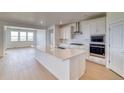 Bright kitchen features a large island, white cabinets, stainless steel appliances, and hardwood floors at 680 Tubman Dr, Elizabeth, CO 80107