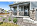 Inviting front porch with stone accents, providing a cozy outdoor seating area and a welcoming entrance at 9196 Rifle St, Commerce City, CO 80022