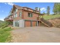 A captivating exterior showing a beautiful log cabin, featuring a garage and adjacent staircase at 25704 Shiloh, Conifer, CO 80433