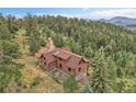 Aerial view featuring a charming log cabin with a rustic roof, surrounded by a dense forest at 25704 Shiloh, Conifer, CO 80433