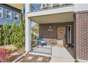 Inviting front porch with brick facade, covered entry, seating, and manicured landscaping at 11216 Uptown Ave, Broomfield, CO 80021