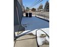 A snowy backyard features a chain-link fence, and trash cans near the side of the house at 2302 S Raleigh St, Denver, CO 80219