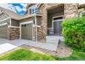 Close up of the exterior of a home with stone accents, a gray two car garage and the covered front entryway at 5010 Persimmon Ln, Castle Rock, CO 80109