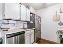 Well-lit kitchen with stainless steel appliances, white cabinets, stylish backsplash, and dark wood floors at 10150 E Virginia Ave # 19-303, Denver, CO 80247