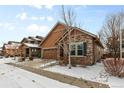 Single-Gathering home with a two-car garage and appealing stone and wood exterior, complemented by a snow-covered yard at 6592 Club Villa Rd, Parker, CO 80134