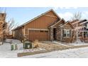 Inviting single-Gathering home with a two-car garage, showcasing a blend of stone and siding, set against a snowy front yard at 6592 Club Villa Rd, Parker, CO 80134