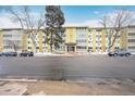 Low-rise apartment building features large windows, yellow siding, and well-maintained landscaping at 580 S Clinton St # 11A, Denver, CO 80247