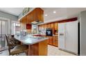 Functional kitchen with wood cabinets, cooktop island, and a white refrigerator at 663 S Xenon Ct, Lakewood, CO 80228