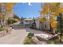 Beautiful home exterior with three-car garage, mature trees, and long driveway at 24768 Foothills N Dr, Golden, CO 80401