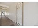 Neutral hallway leading to a bright white door, with wall mounted light fixtures and carpeted floor at 875 E 78Th Ave # 9-2, Denver, CO 80229