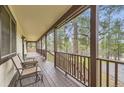 Inviting covered porch with wood floors and views of the surrounding wooded landscape at 4305 Red Rock Dr, Larkspur, CO 80118